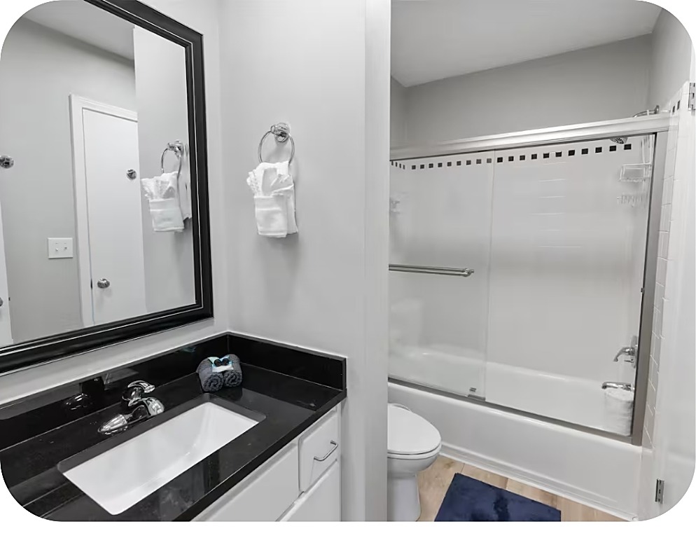 Baño con encimera oscura y ducha-bañera